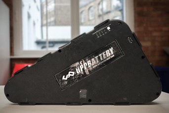 Triangular black battery pack with a black sticker and white writing that reads UPPBATTERY
